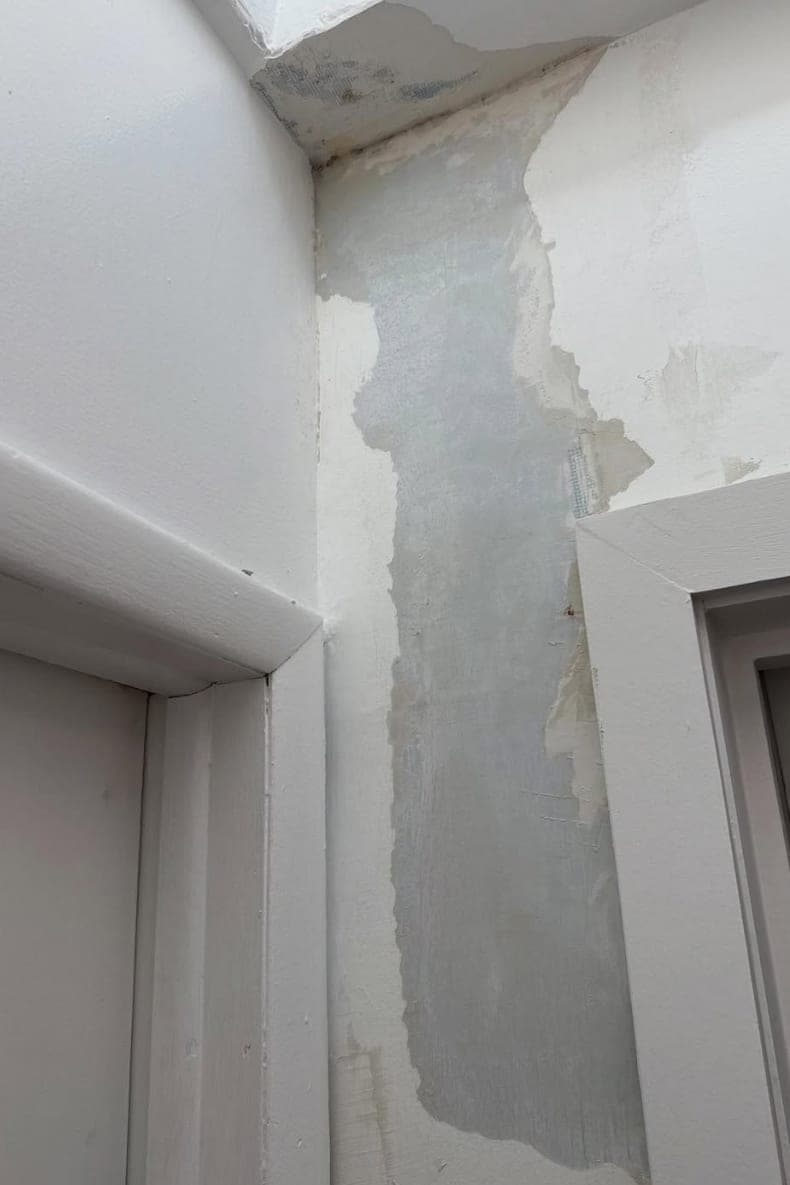 Before: Damaged wall, peeling paint and cracked plaster.